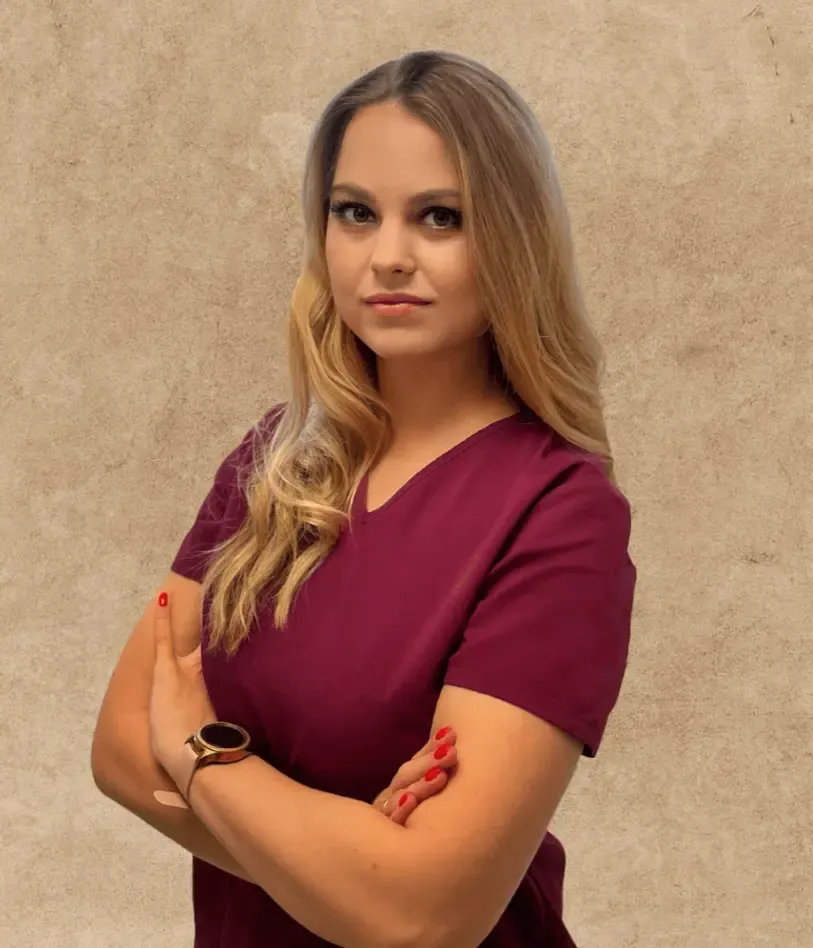 Dr. Lajkó Kitti bordó munkaruhában, karba tett kézzel